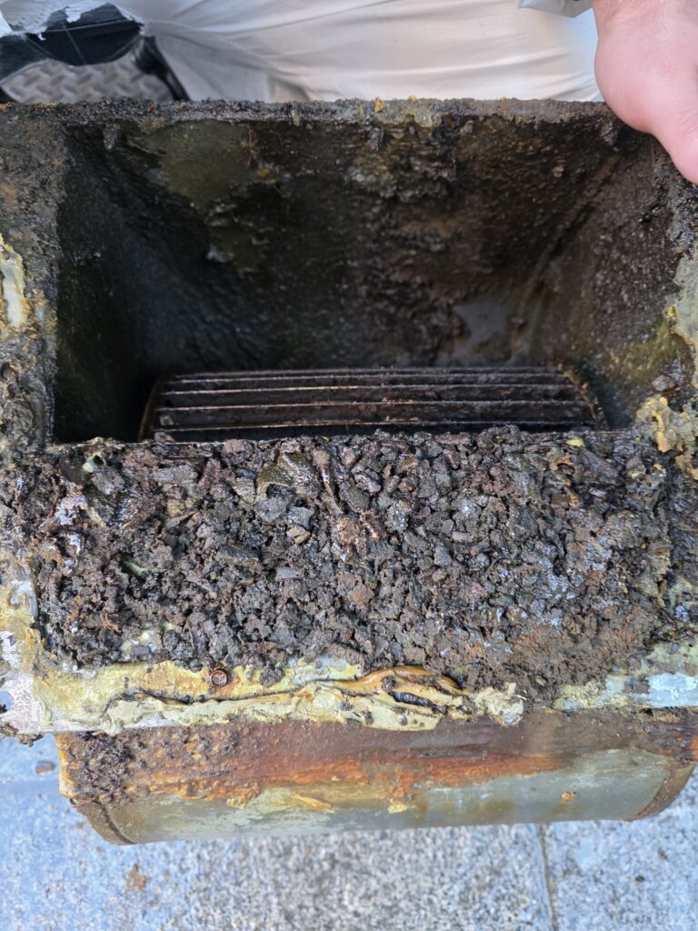 Section de conduit d'extraction démontée, tapissée d'une couche épaisse de graisse solidifiée, dans un restaurant de Cergy
