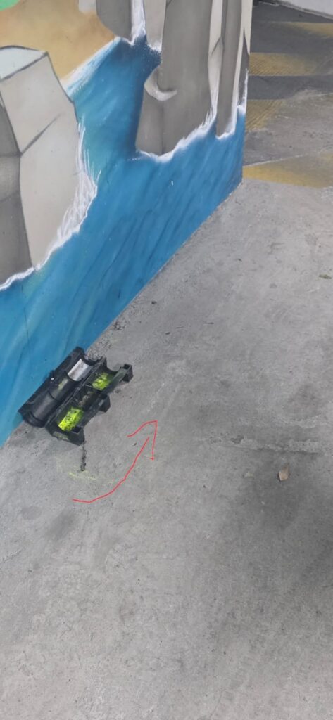 Poudre fluorescente jaune-vert dans un poste d'appâtage rongeur et traînée au sol, dans le parking souterrain d'une copropriété de Gennevilliers